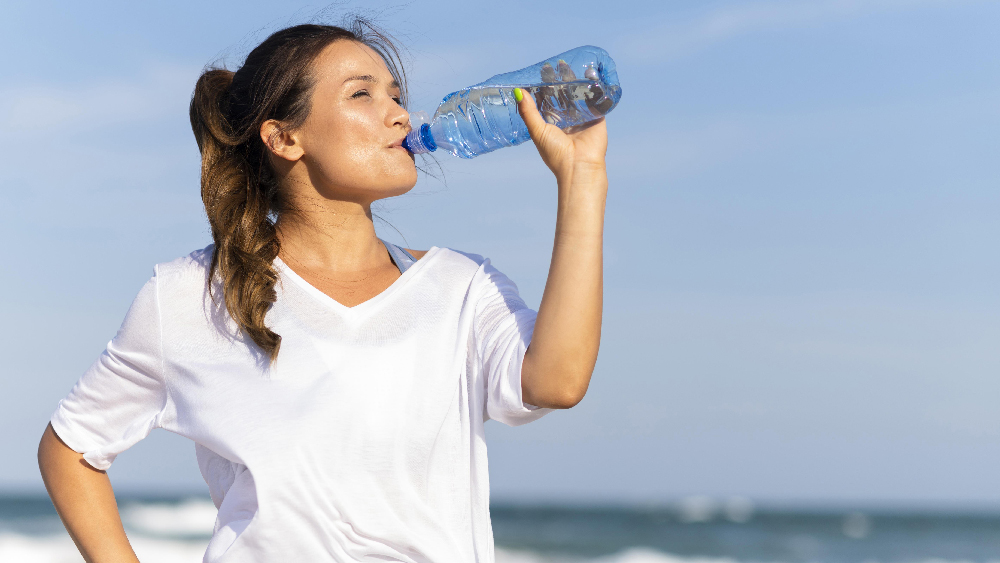 woman staying hydrated drinking water at the beach