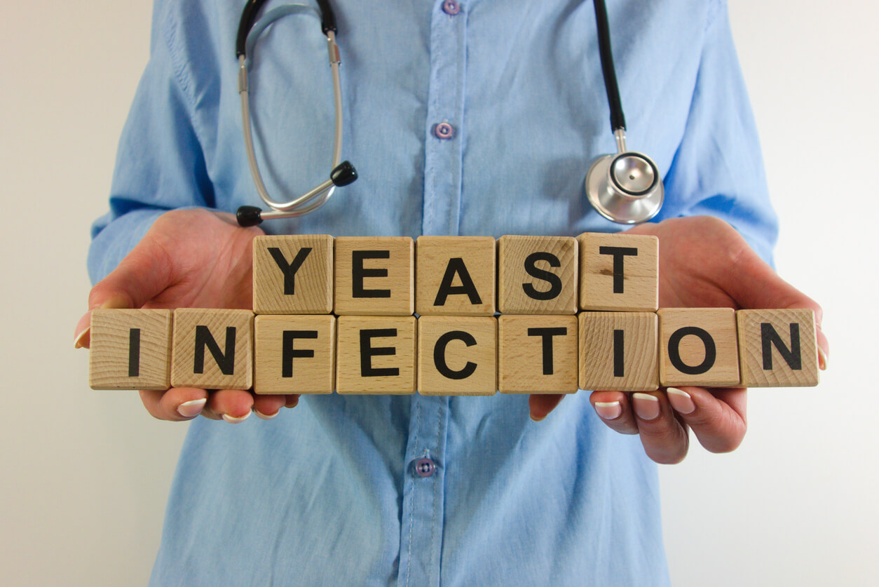 Female doctor holding text yeast infection from wooden blocks.