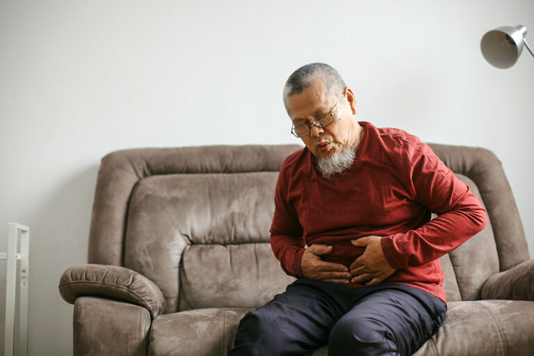 Shot Of Unhealthy Asian Old Man With gut health and stomachache n The Couch In The Living Room At Home
