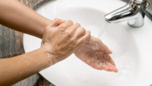 close up of hands taking care of winter skin issues by washing them with soap over a bathroom sink