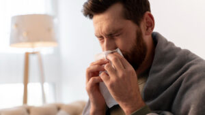 a man with common winter illnesses blowing into a napkin
